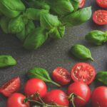 photography of tomatoes near basil leaves