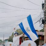 man waving an el salvadoran flag on the street
